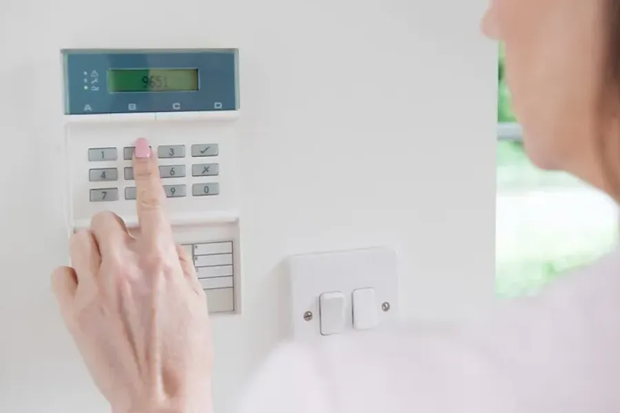 person inputting code into alarm panel