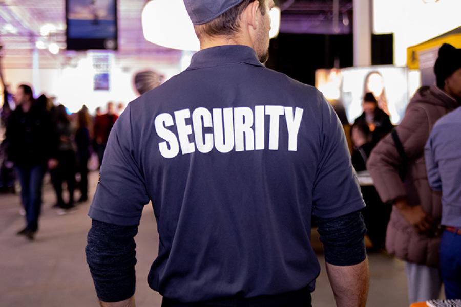 closeup of back of security guard in uniform patrolling event