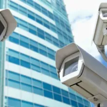 three security cameras with skyscraper in the background
