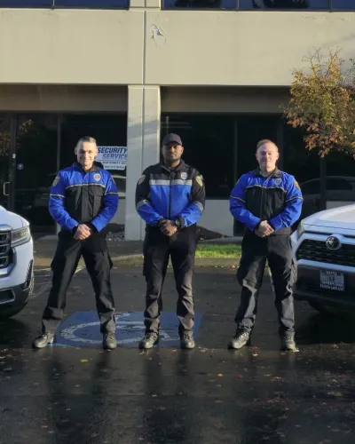 three security officers standing between two patrol vehicles